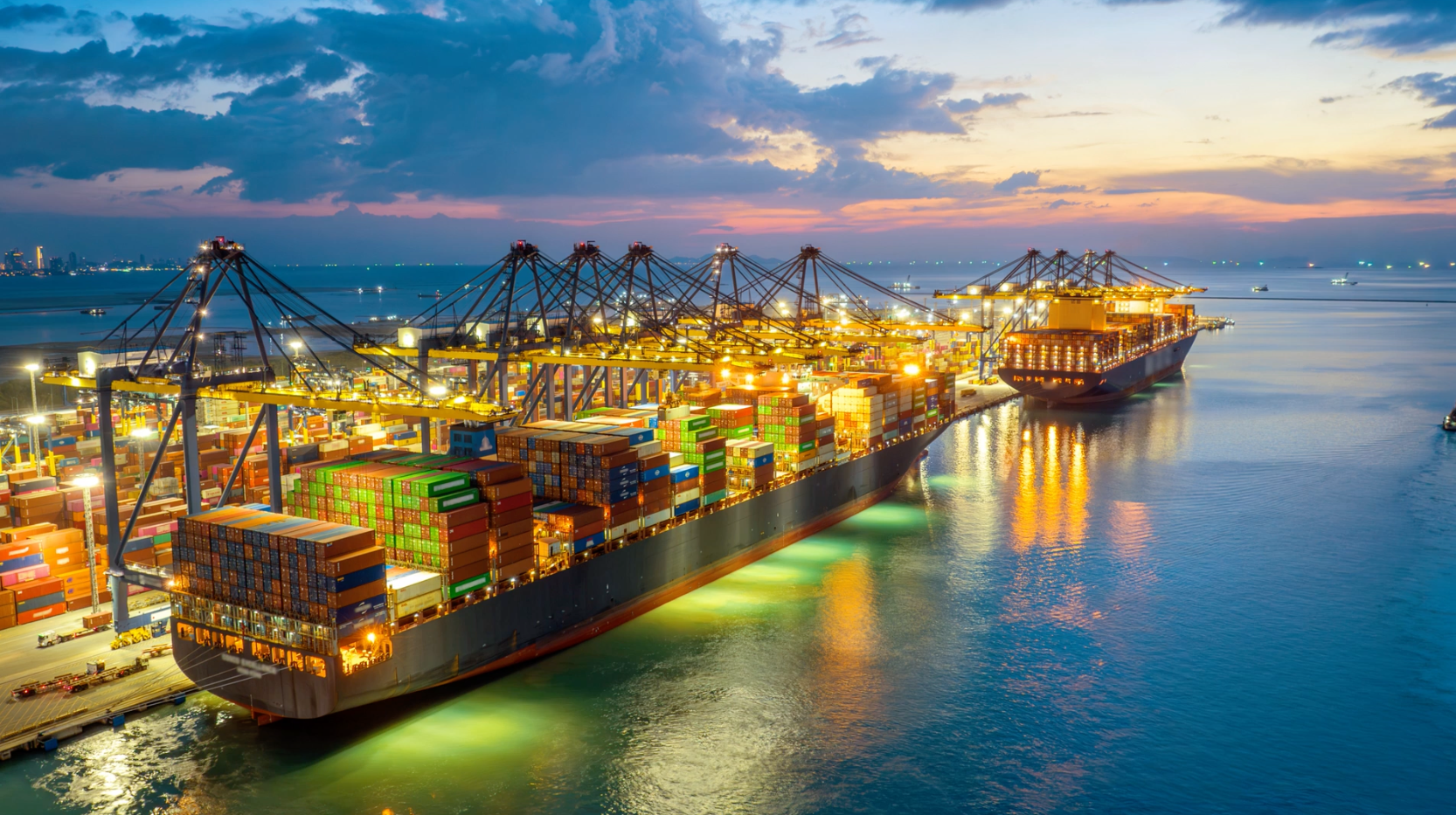 Containerschiff im Hafen bei Nacht mit modernen Kränen beladen