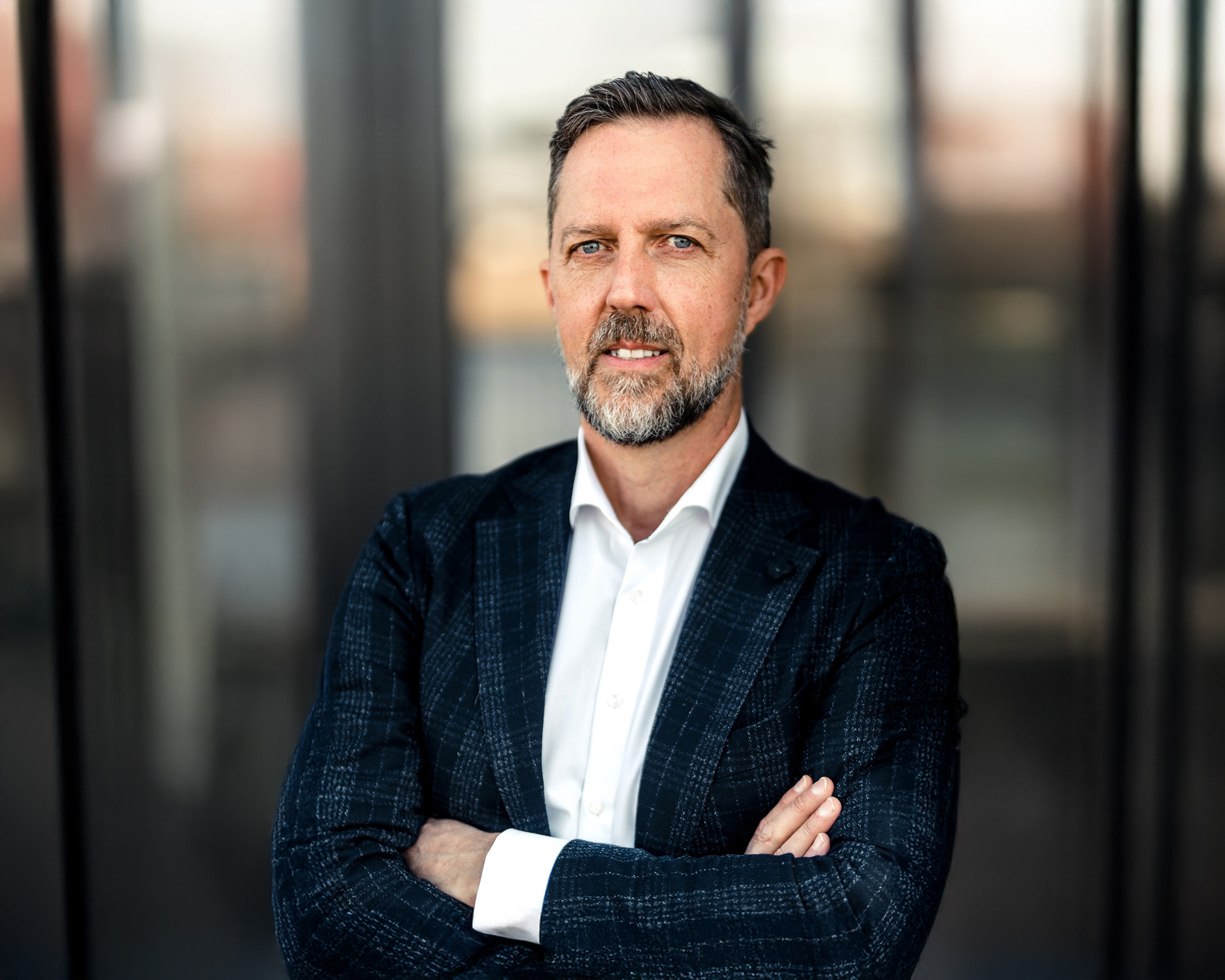 Professionelles Porträt eines Mannes im Business-Outfit vor modernem Hintergrund