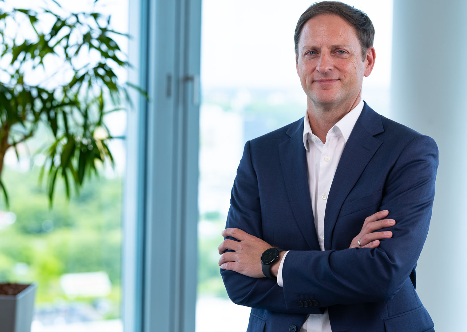 Geschäftsmann in dunklem Anzug posiert selbstbewusst im modernen Büro