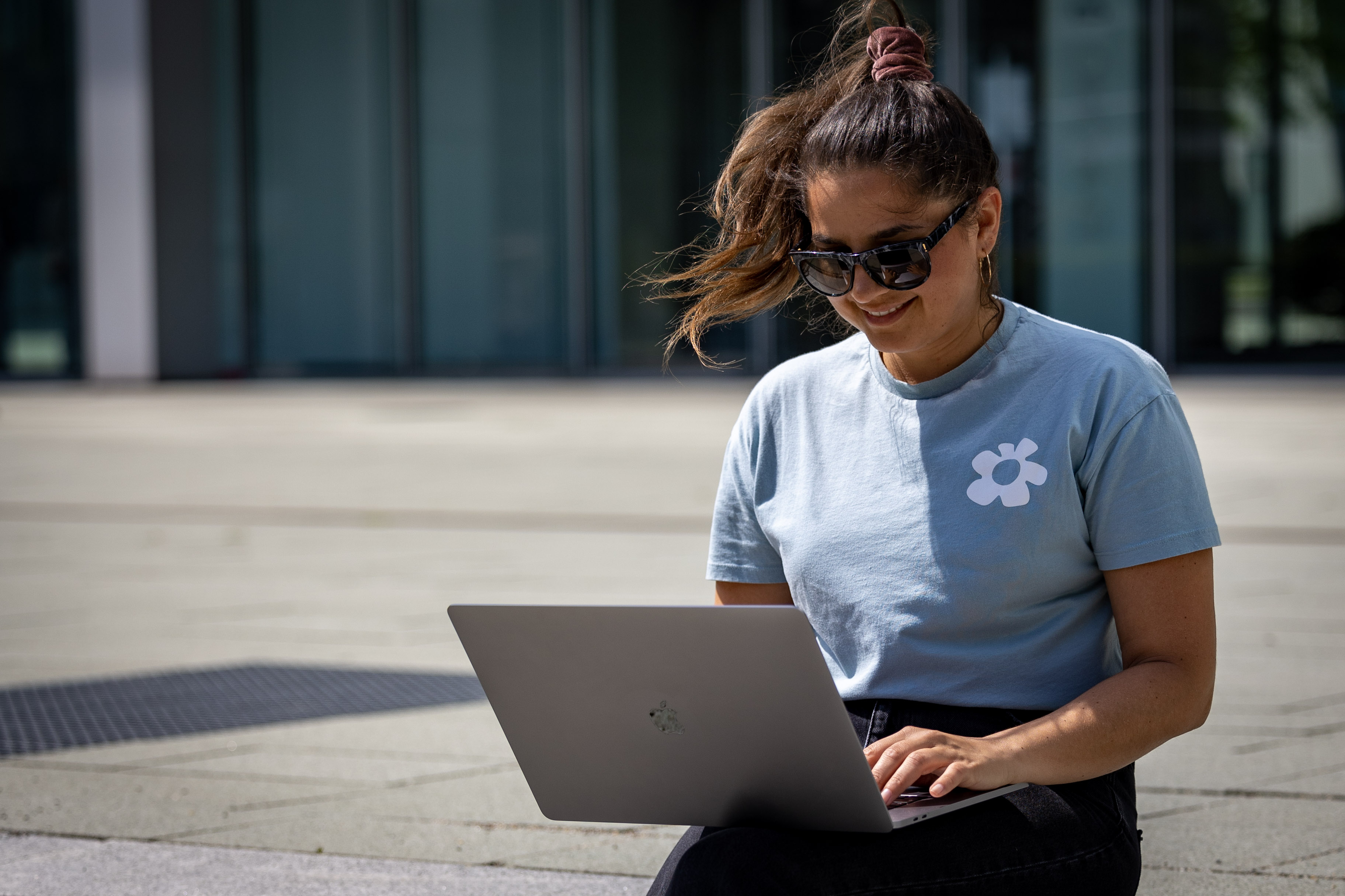 Junge Frau arbeitet draußen konzentriert an ihrem Laptop