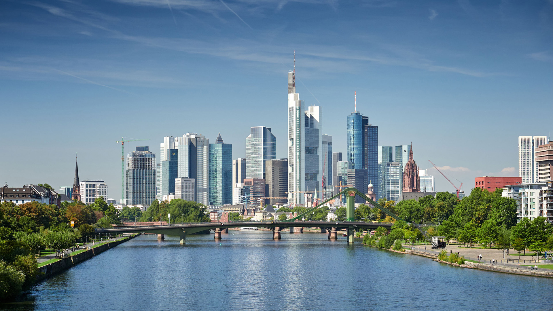 Skyline einer deutschen Großstadt mit Fluss und grüner Brücke